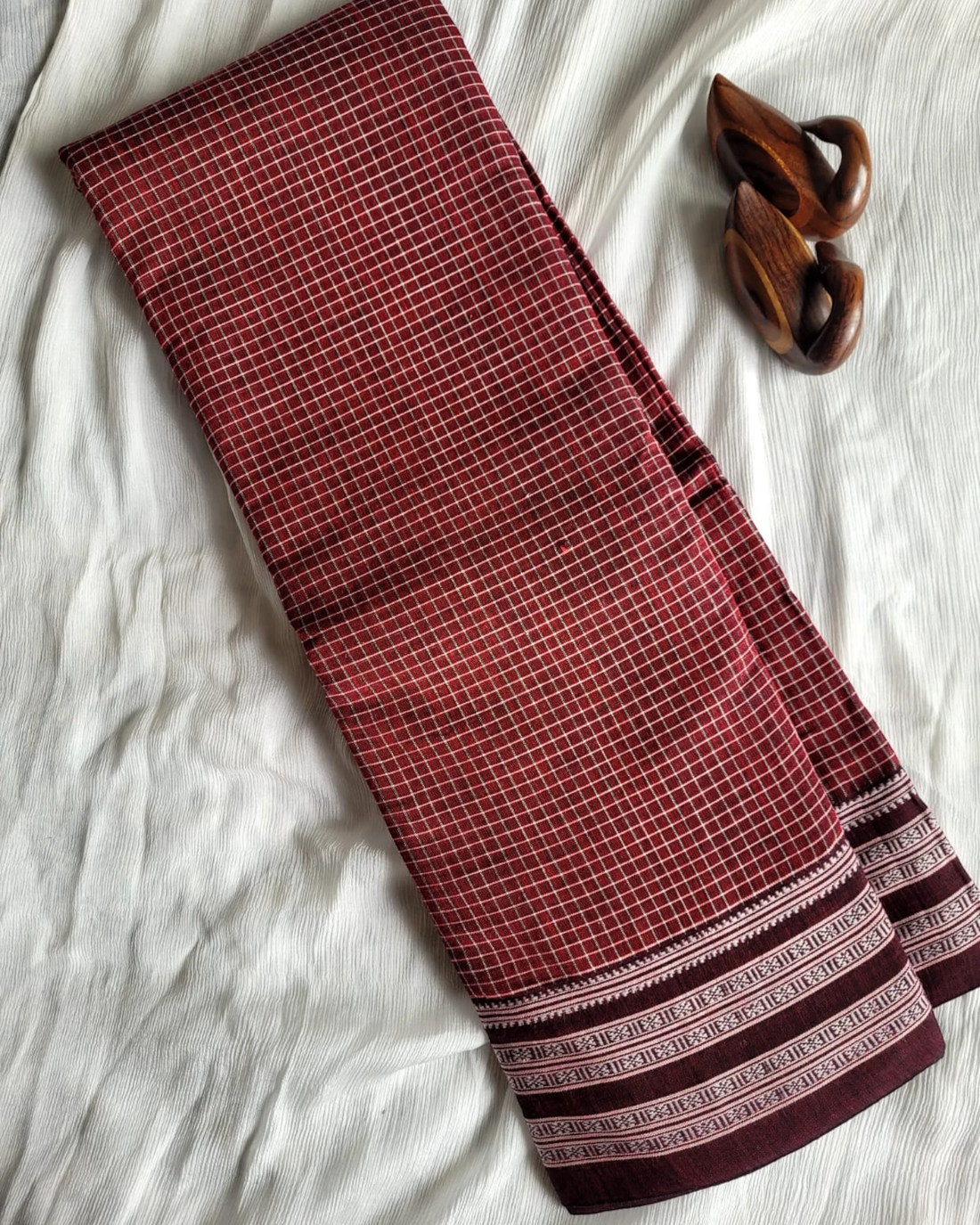Folded fabric with red and brown patterns on a white surface