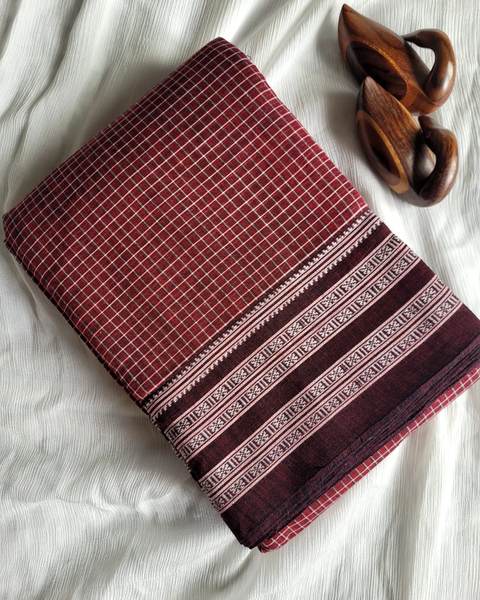 Folded fabric with red and brown patterns on a white surface